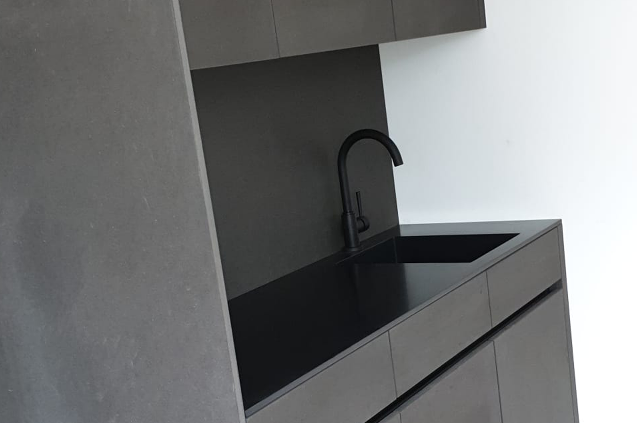 5 Moderne, graue Küchenzeile mit schwarzem Wasserhahn und Spüle vor weißer Wand. Minimalistisches Design.